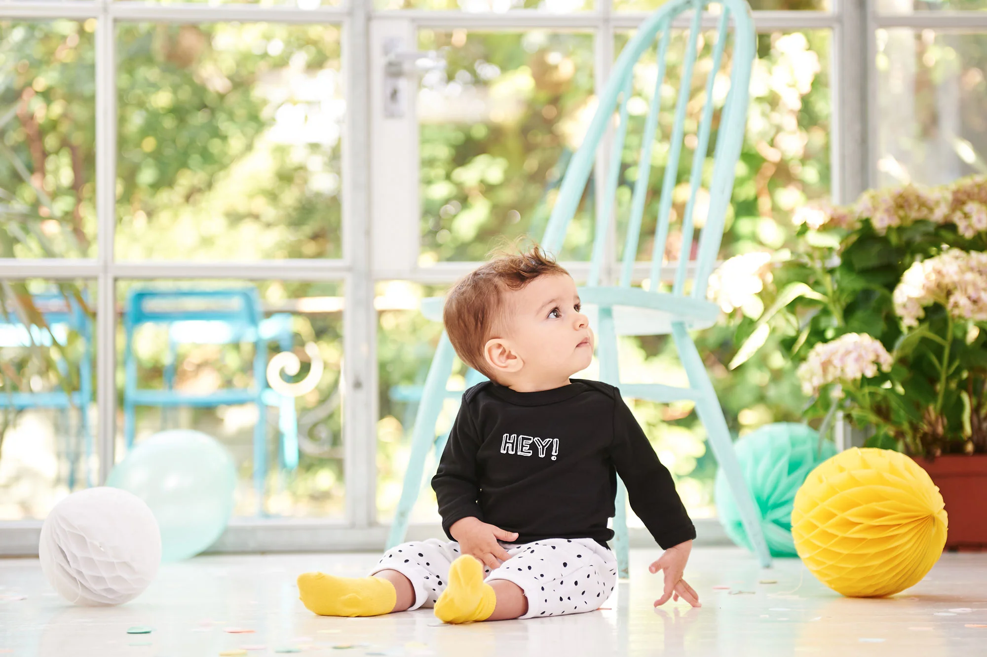 a baby in a Hey printed t-shirt and patterned trousers designed